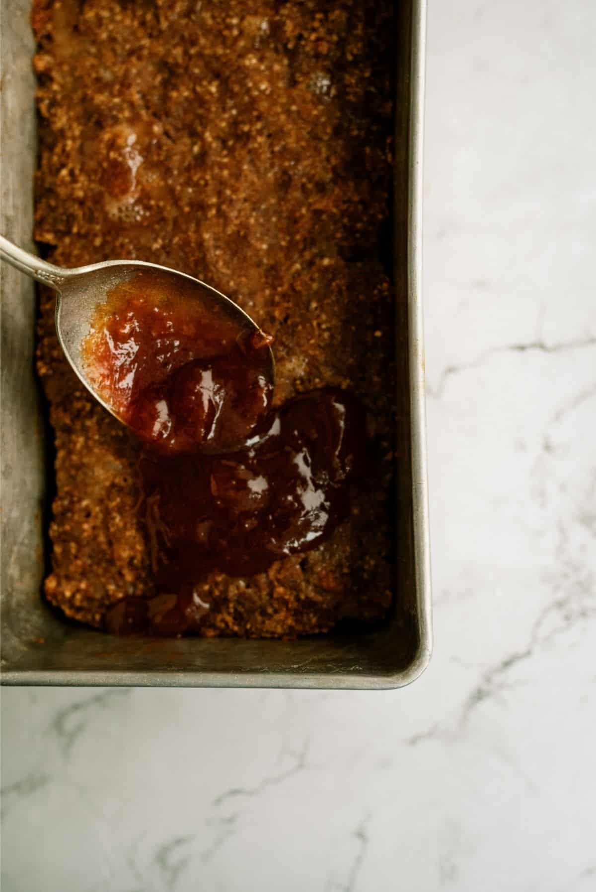 Spooning sauce over baked meatloaf