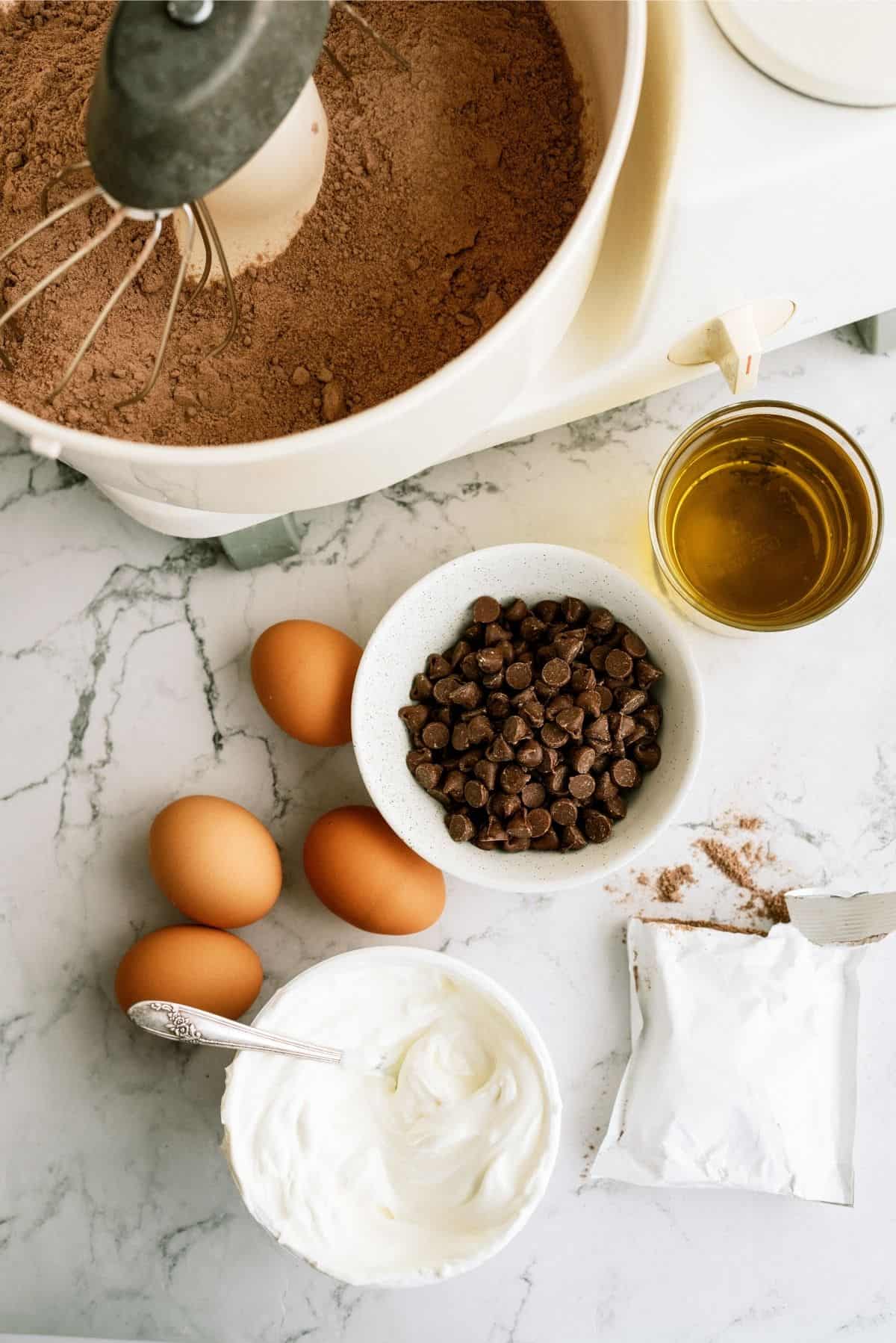 sour cream, pudding mix, oil and chocolate chips with cake batter in a mixing bowl