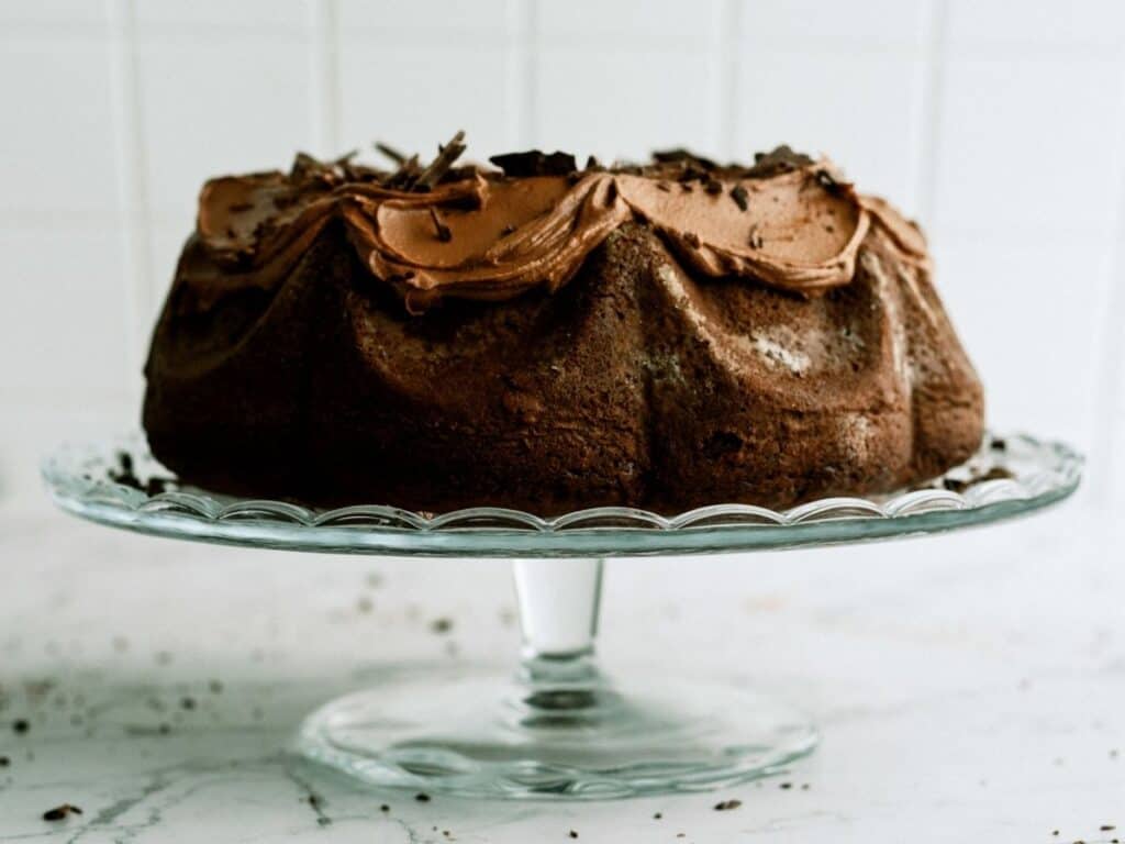 Front view of Triple Chocolate Bundt Cake frosted on a cake stand.