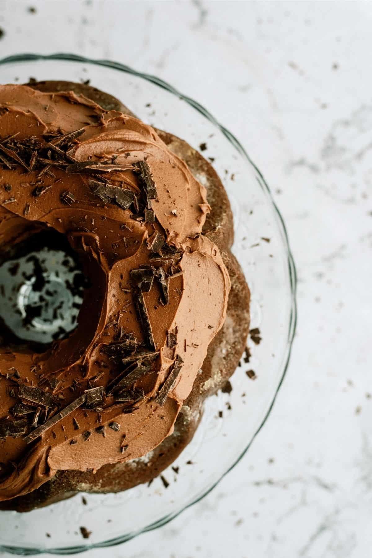 Triple Chocolate Bundt Cake frosted on a glass cake stand