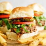 Baked Cheeseburger Sliders on top of a cutting board surrounded by french fries.