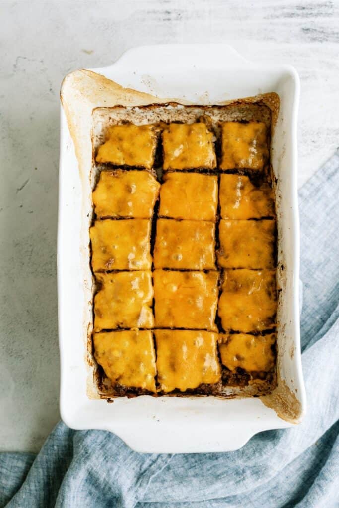 Baked cheeseburger meat sectioned into squares in a baking dish.