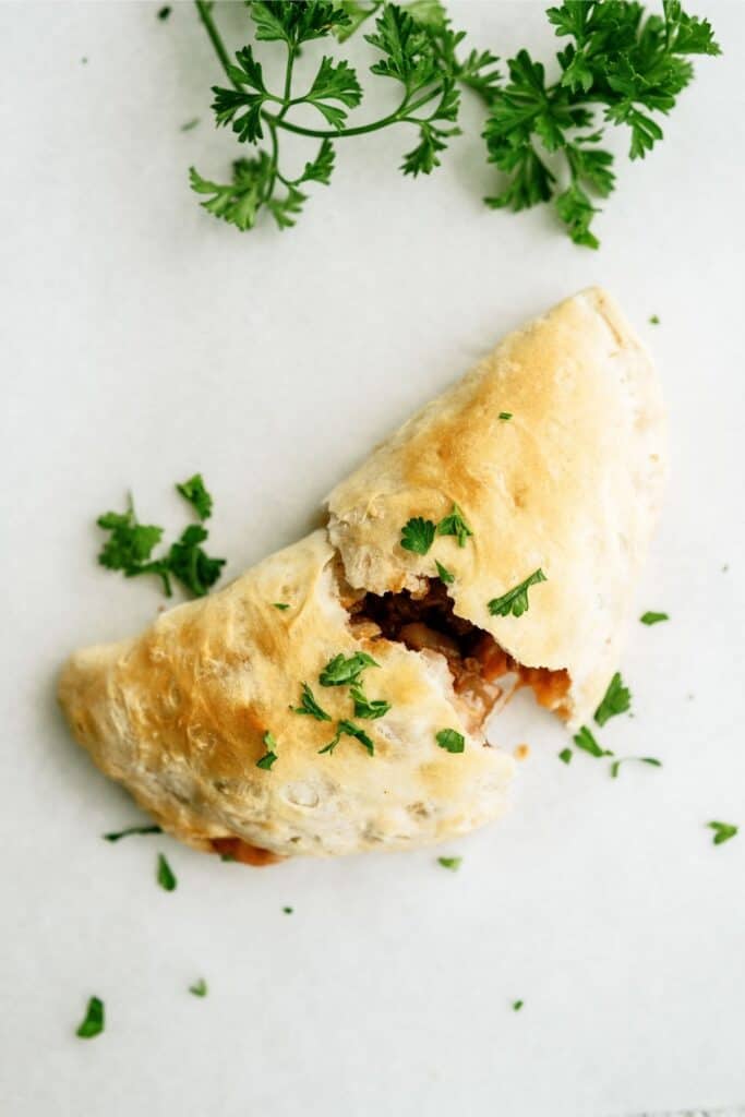 Baked Sloppy Joe broken in half on a white background.
