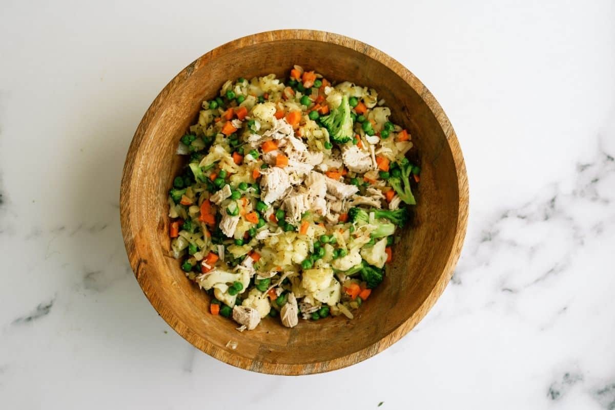 Cooked chicken and vegetables mixed in a wooden bowl