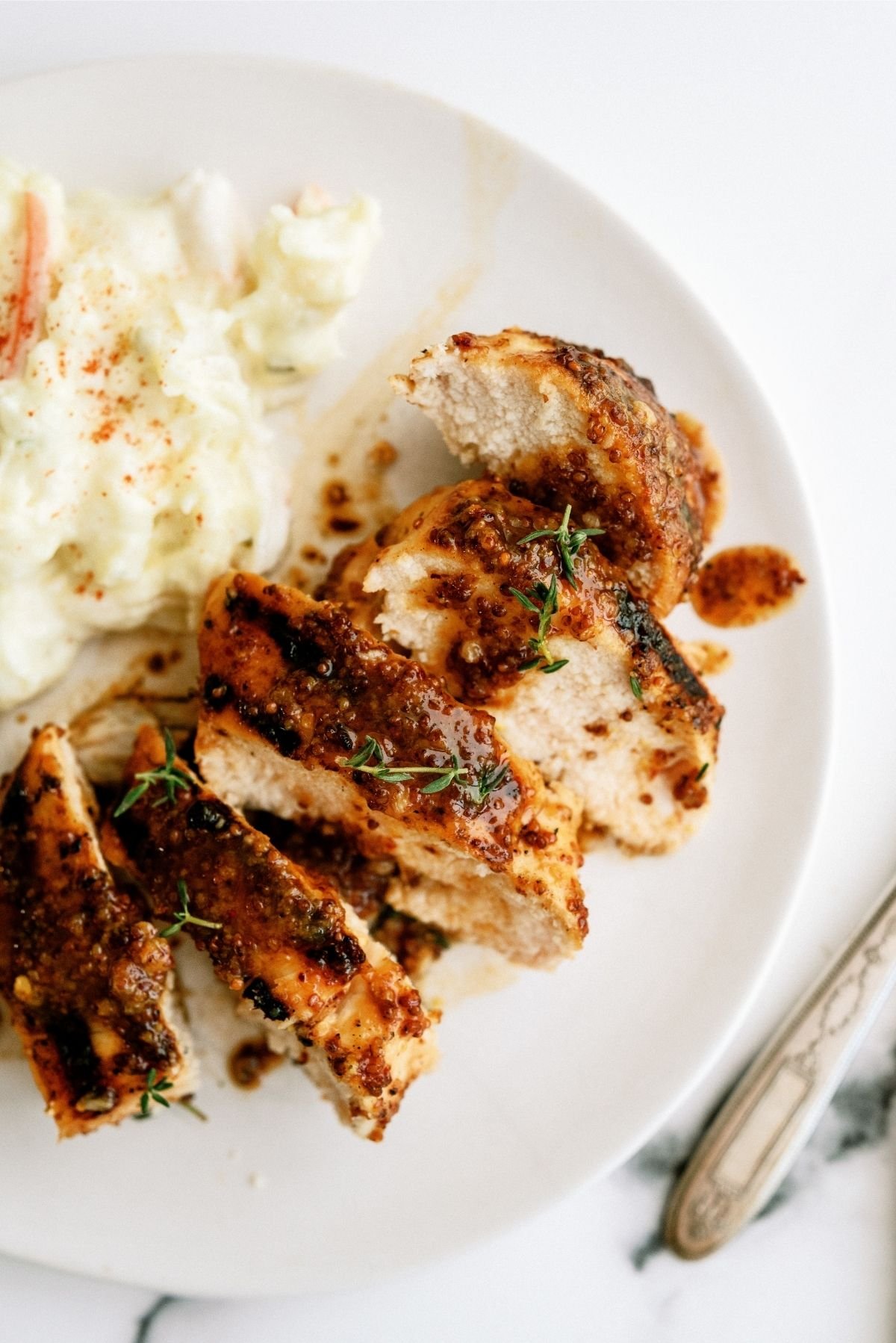 Sliced Grilled Honey Mustard Chicken on a plate served with potato salad
