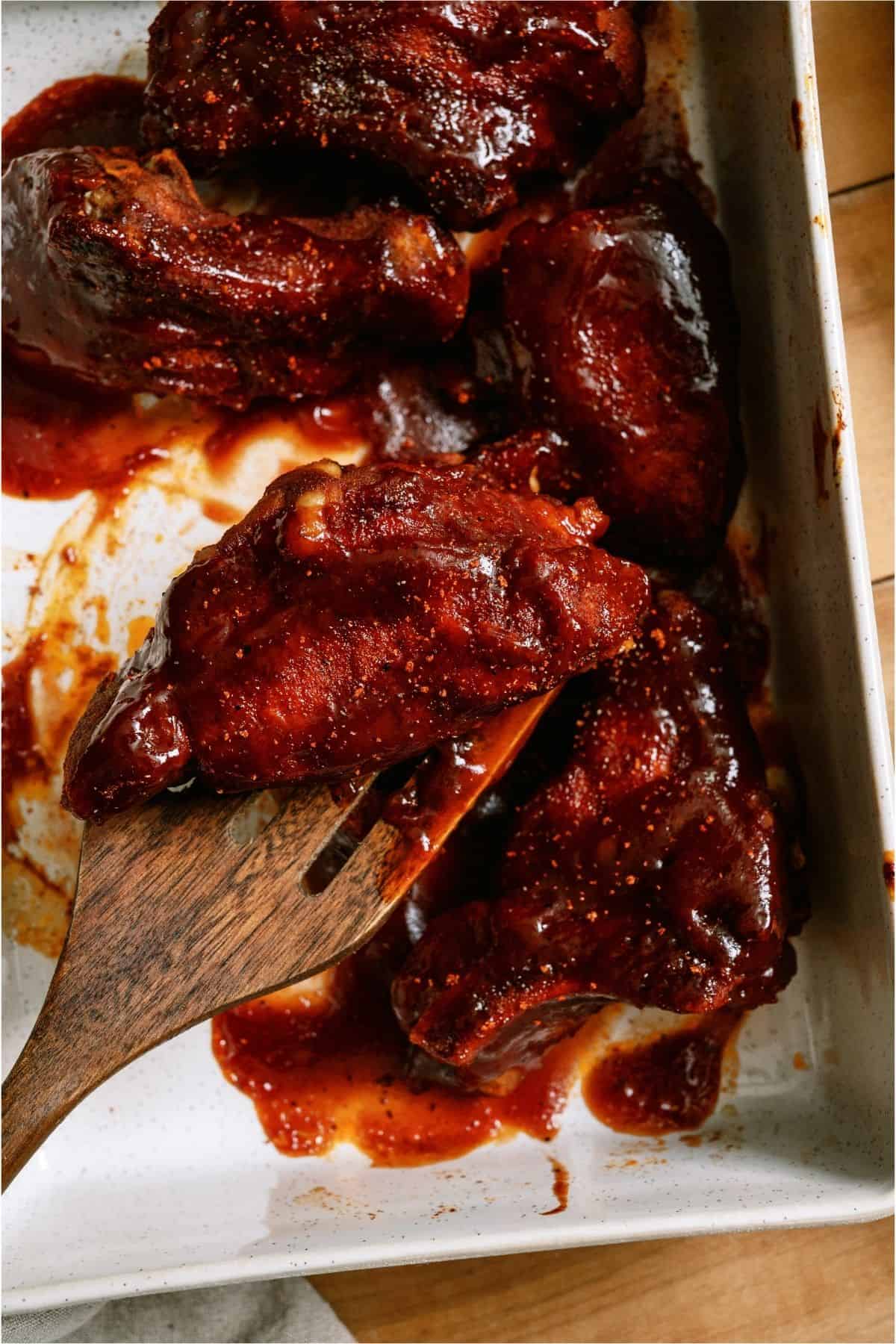 A spatula lifting a rib out of the baking dish.