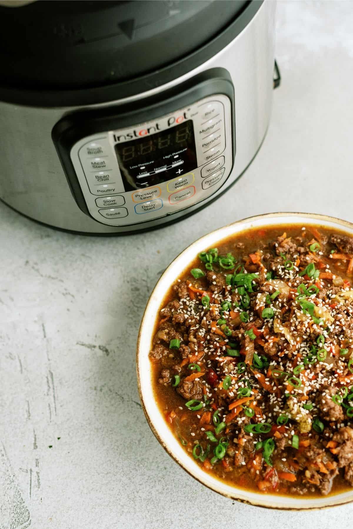 Instant Pot Ground Turkey Teriyaki Rice Bowl with an Instant Pot in the back ground