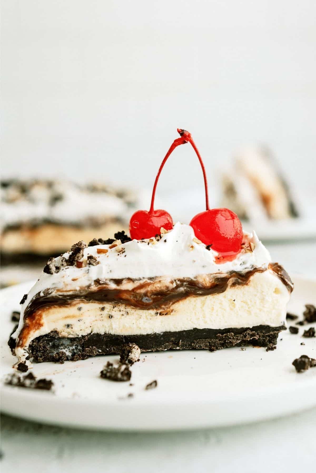 Slice of No Bake Mississippi Mud Ice Cream Pie on a white plate topped with cherries