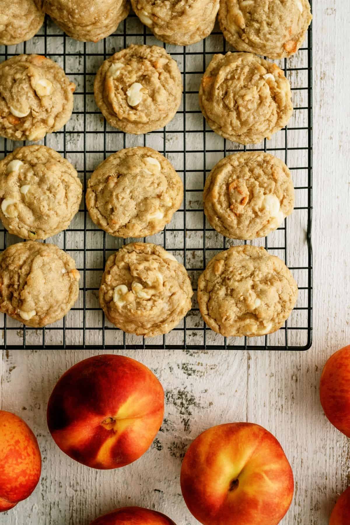 Peaches and Cream Oatmeal Cookies on a cooling rack with fresh peaches