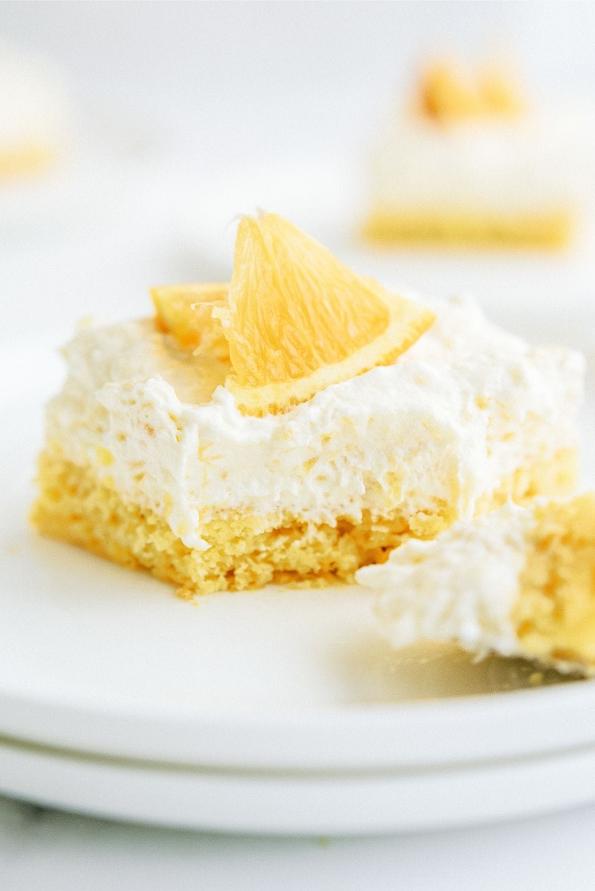 A slice of Pineapple Orange Cake Recipe (Pig Pickin’ Cake) on stacked white plates