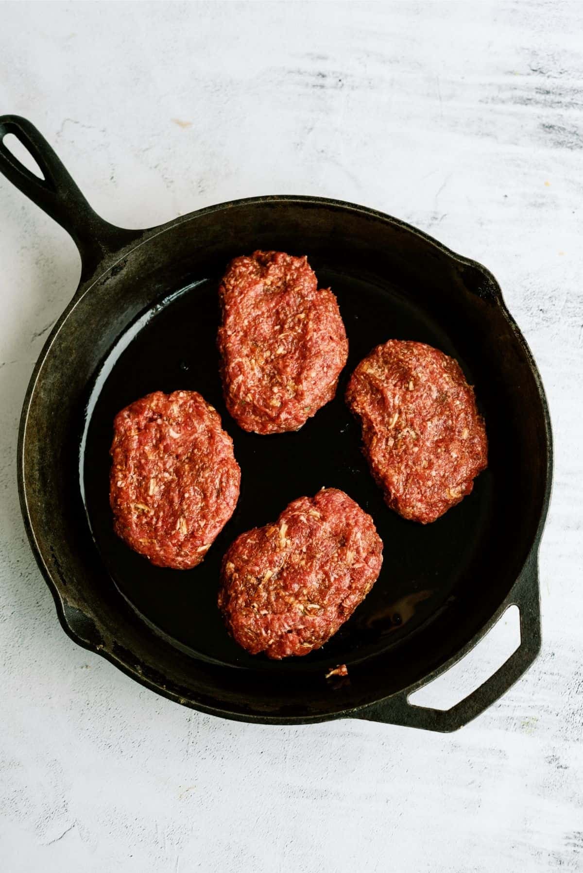 Skillet with 4 uncooked Salisbury Steak patties