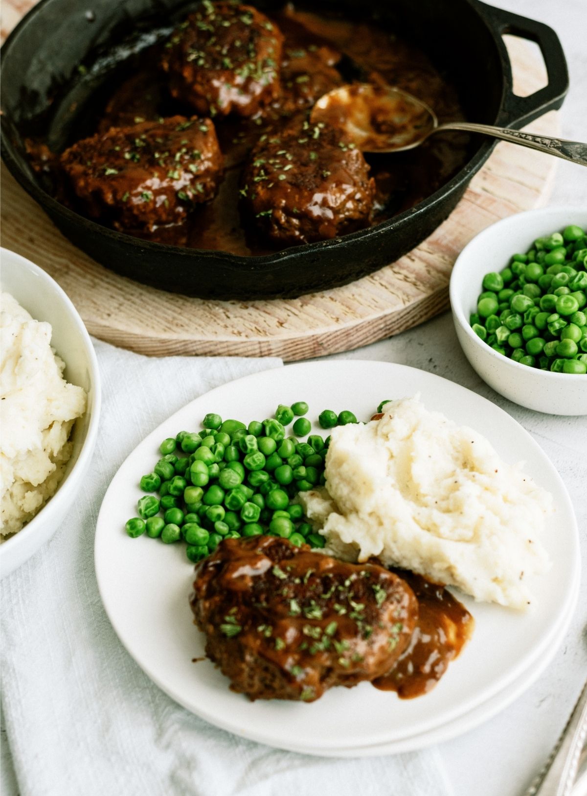 Salisbury Steak on a plate with mashed potatoes and peas
