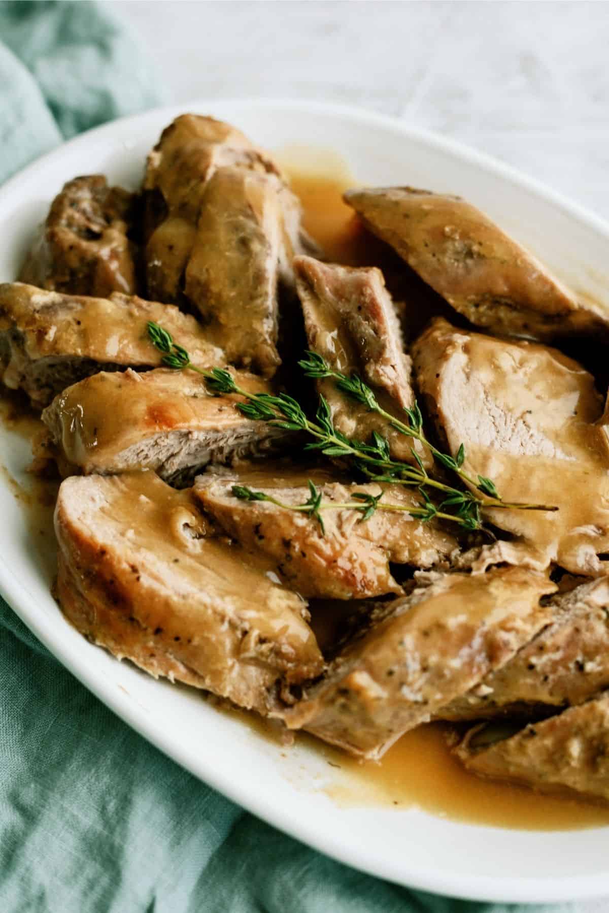 Slow Cooker Maple and Brown Sugar Pork Tenderloin sliced on a serving platter with gravy on top.