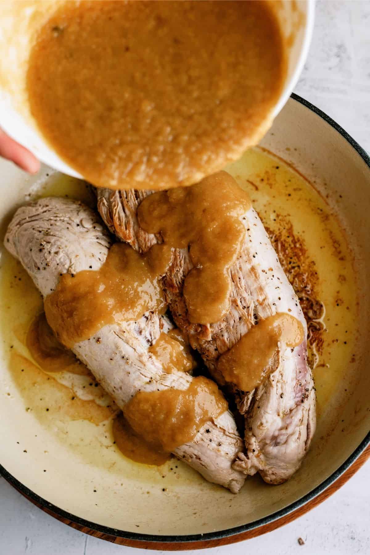 Putting the applesauce mixture on top of seared pork