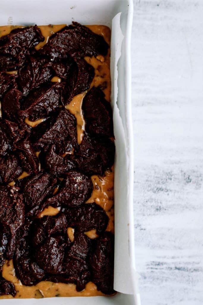 Brownie dough dropped and spread on top of caramel sauce.