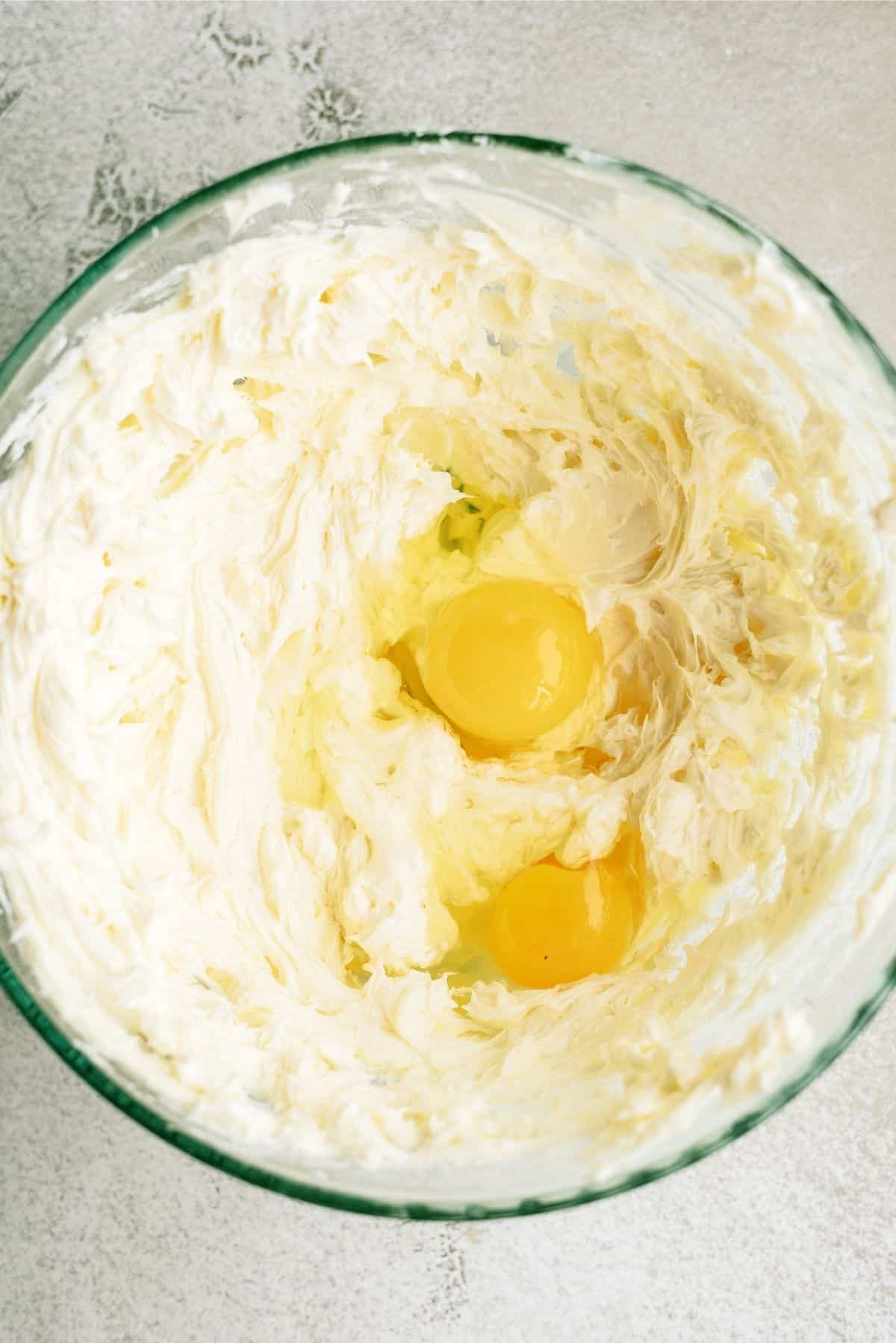Cheesecake filling ingredients mixed together in a glass bowl