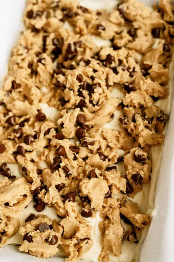 Sprinkled chocolate chip cookie dough on top of cheesecake layer.