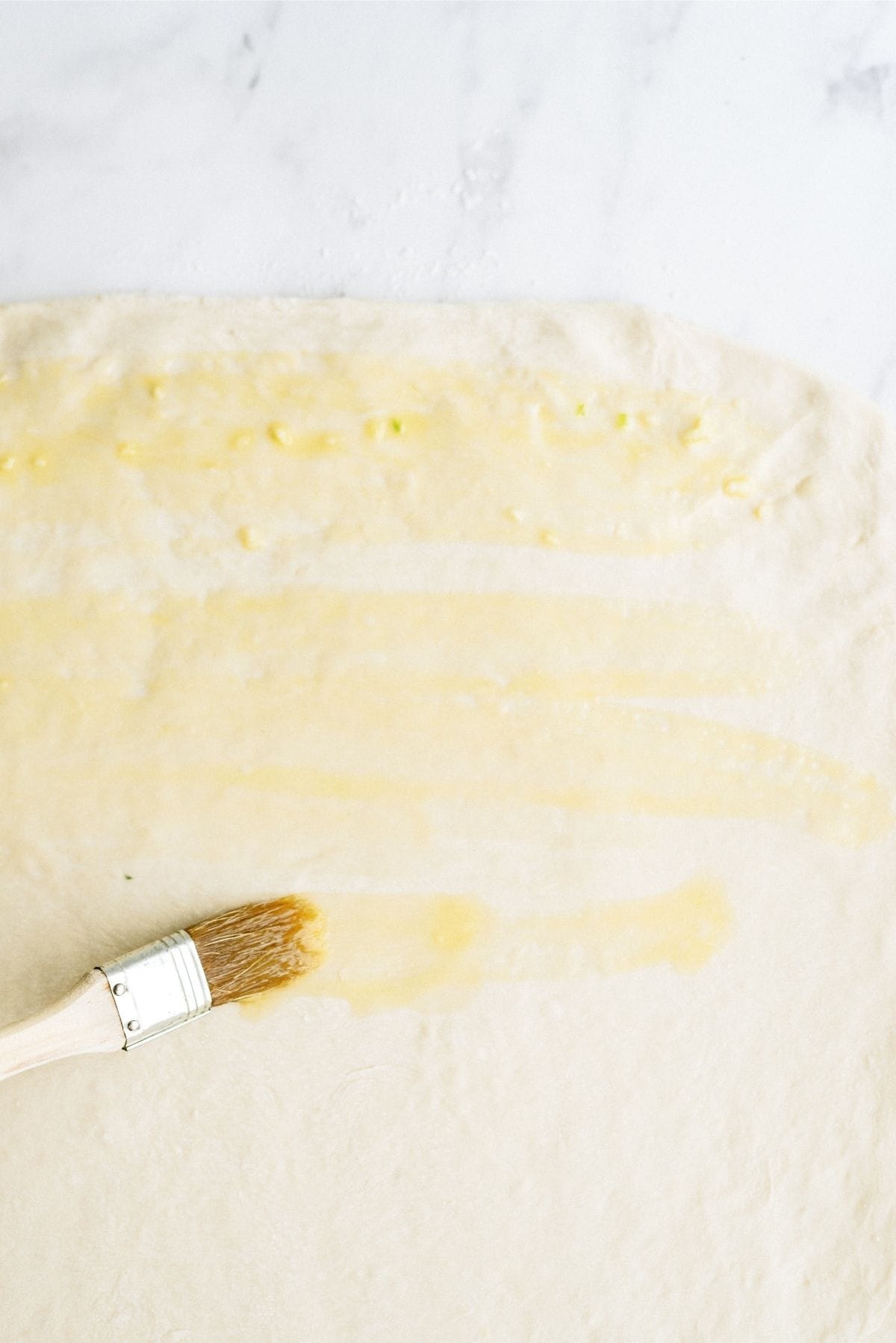 brushing butter mixture on flattened dough