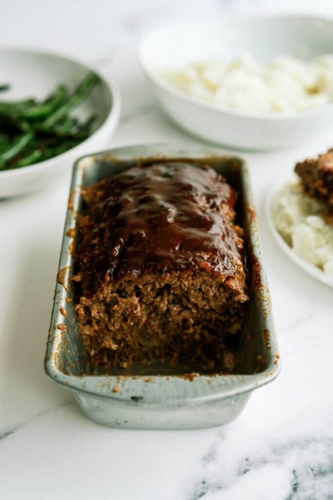 Honey BBQ Meatloaf in loaf pan with half of it missing to show the inside.
