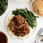 A plate with Honey BBQ Meatloaf served over mashed potatoes with a side of green beans.