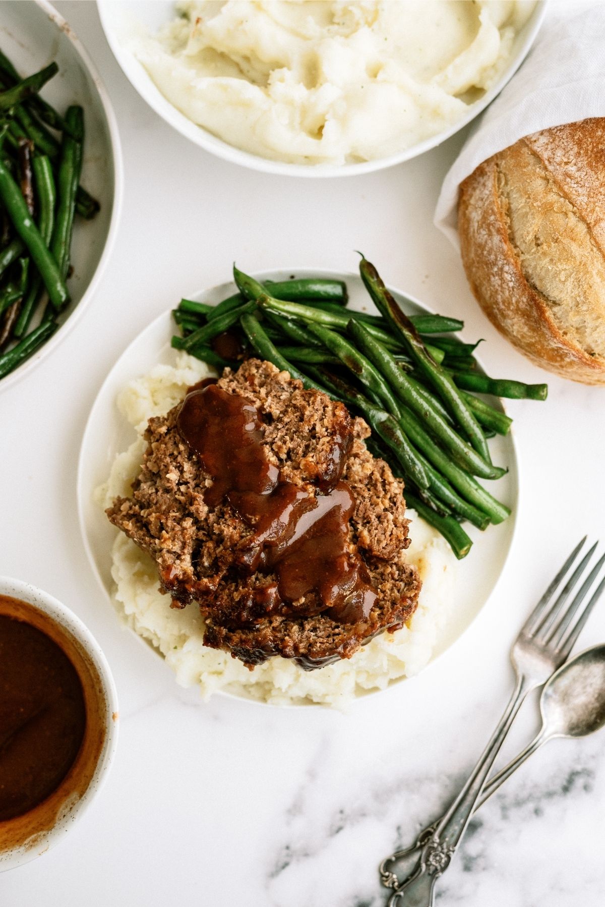 Honey BBQ Meatloaf slices on a plate with mashed potatoes and green beans.