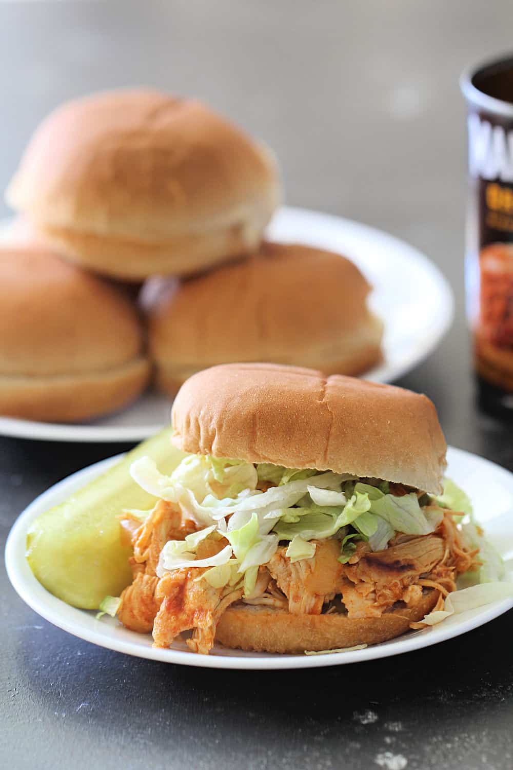 Instant Pot Chicken Sloppy Joes on a bun topped with vegetables and served with pickles