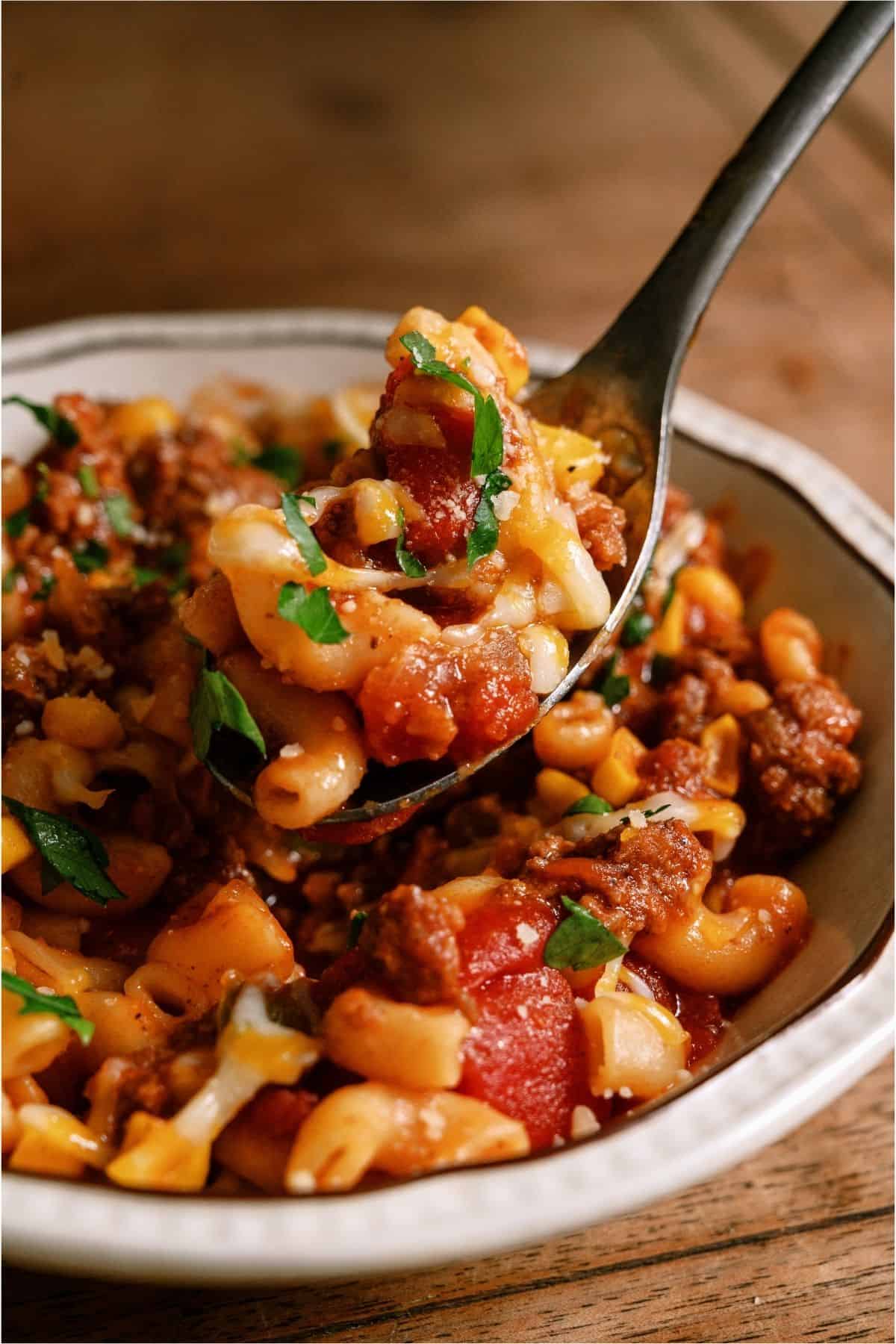 A spoon lifting a bite of Instant Pot Ground Beef Goulash out of a bowl.