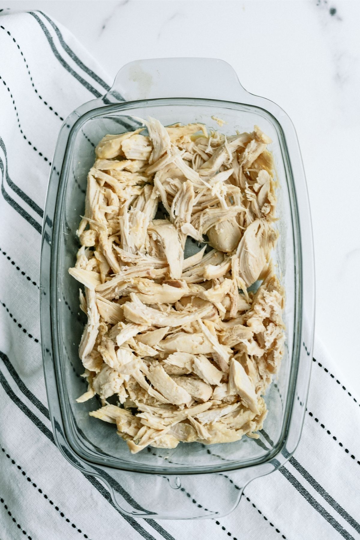 Shredded cooked chicken in a 9x13 glass dish