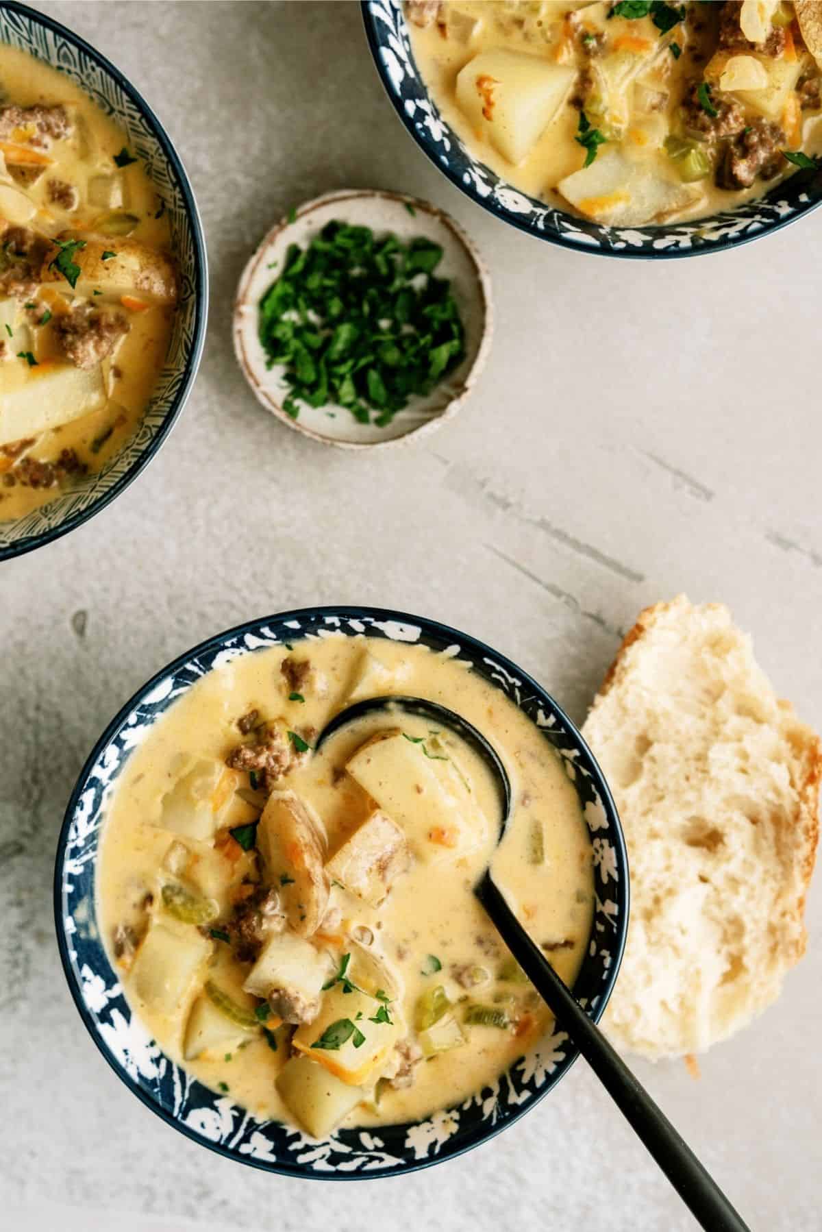 The Best Cheeseburger Soup Recipe (Cheesy Ground Beef Soup) in a bowl with a spoon and side of bread