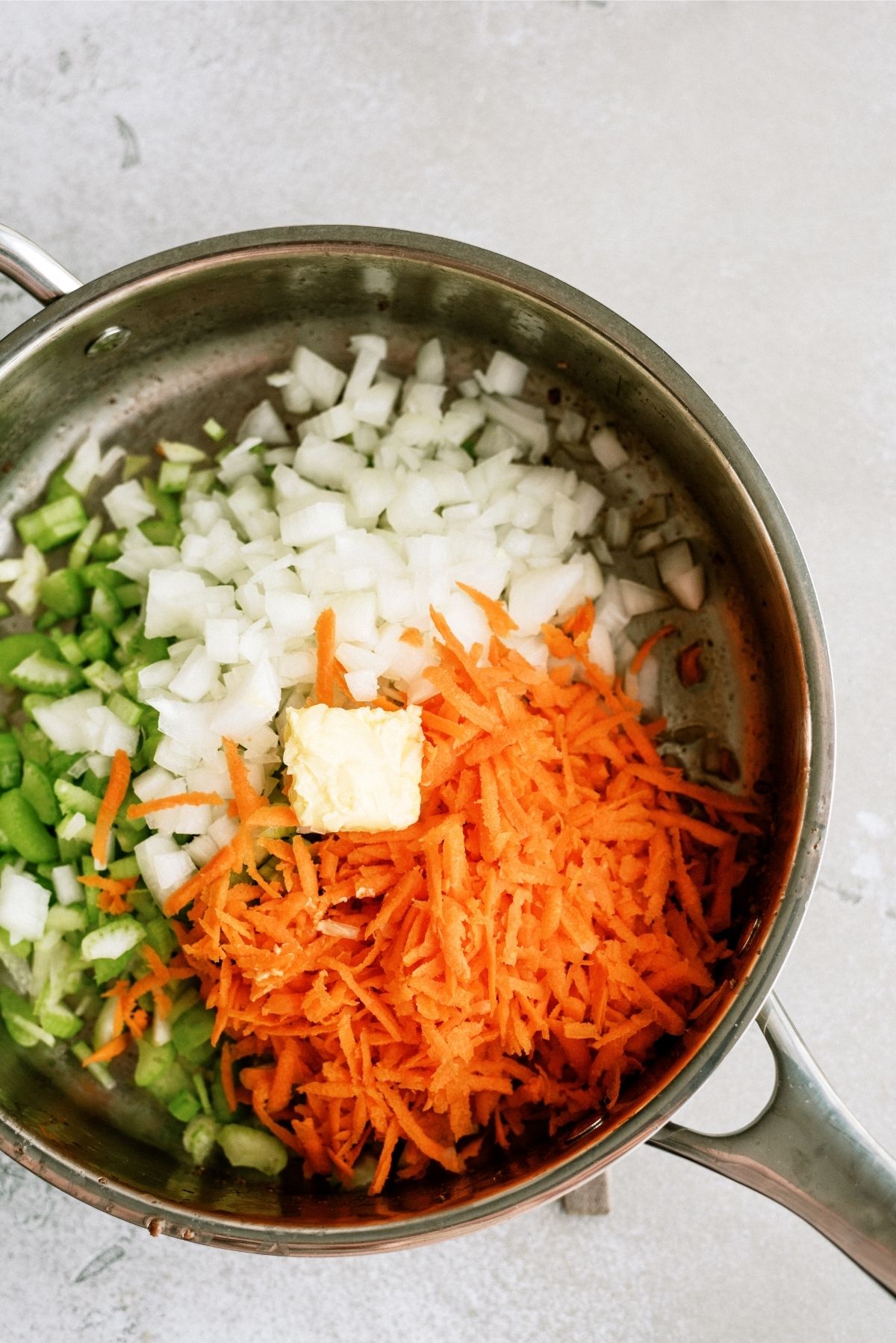 Skillet with butter, onions, celery and shredded carrots