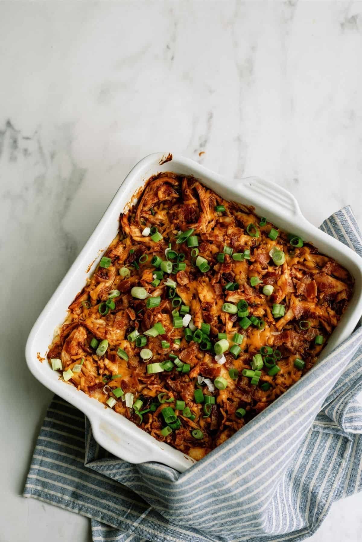 BBQ Chicken and Potato Casserole in a white casserole dish with a striped dish towel