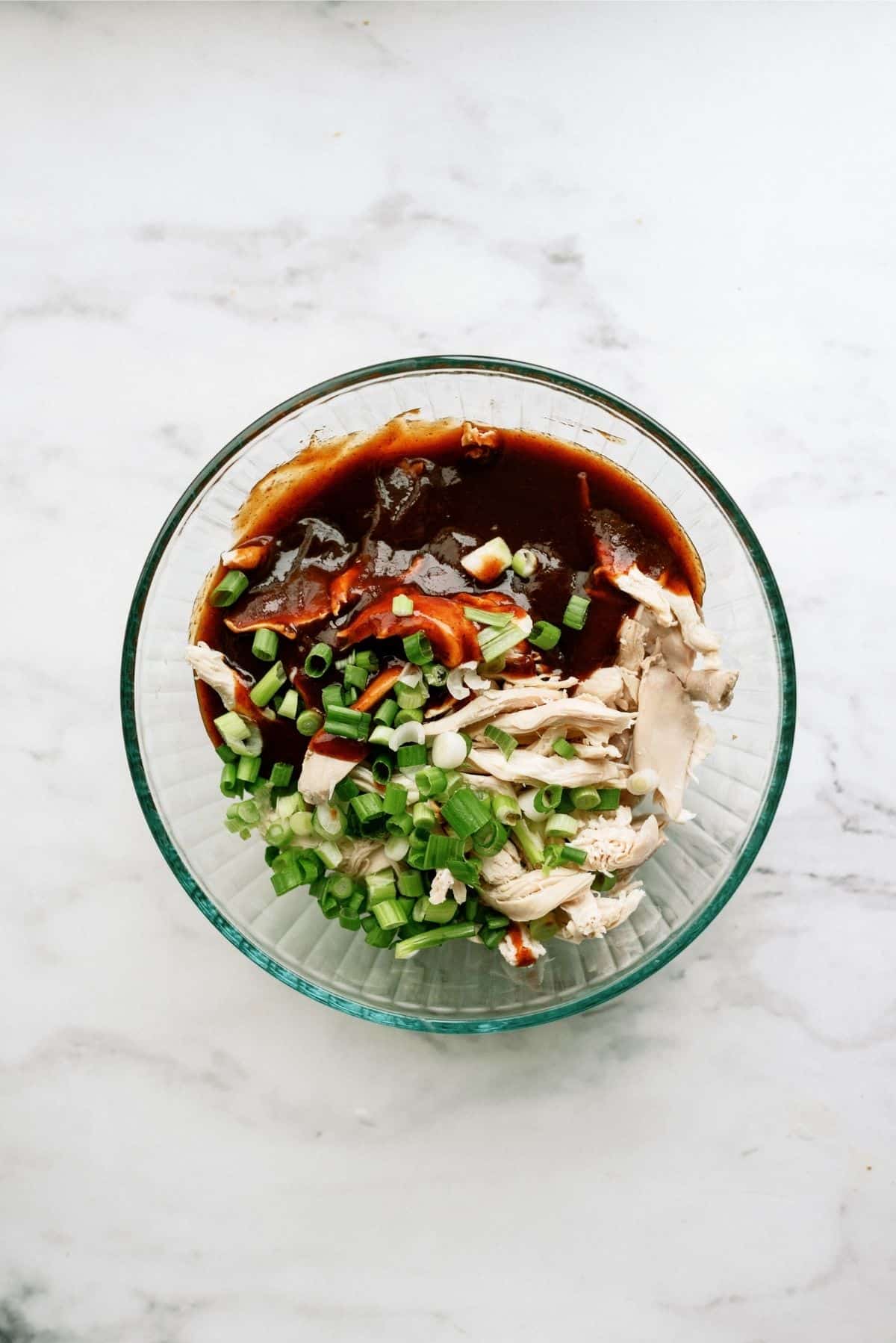 Chicken, BBQ sauce and green onions in a large mixing bowl