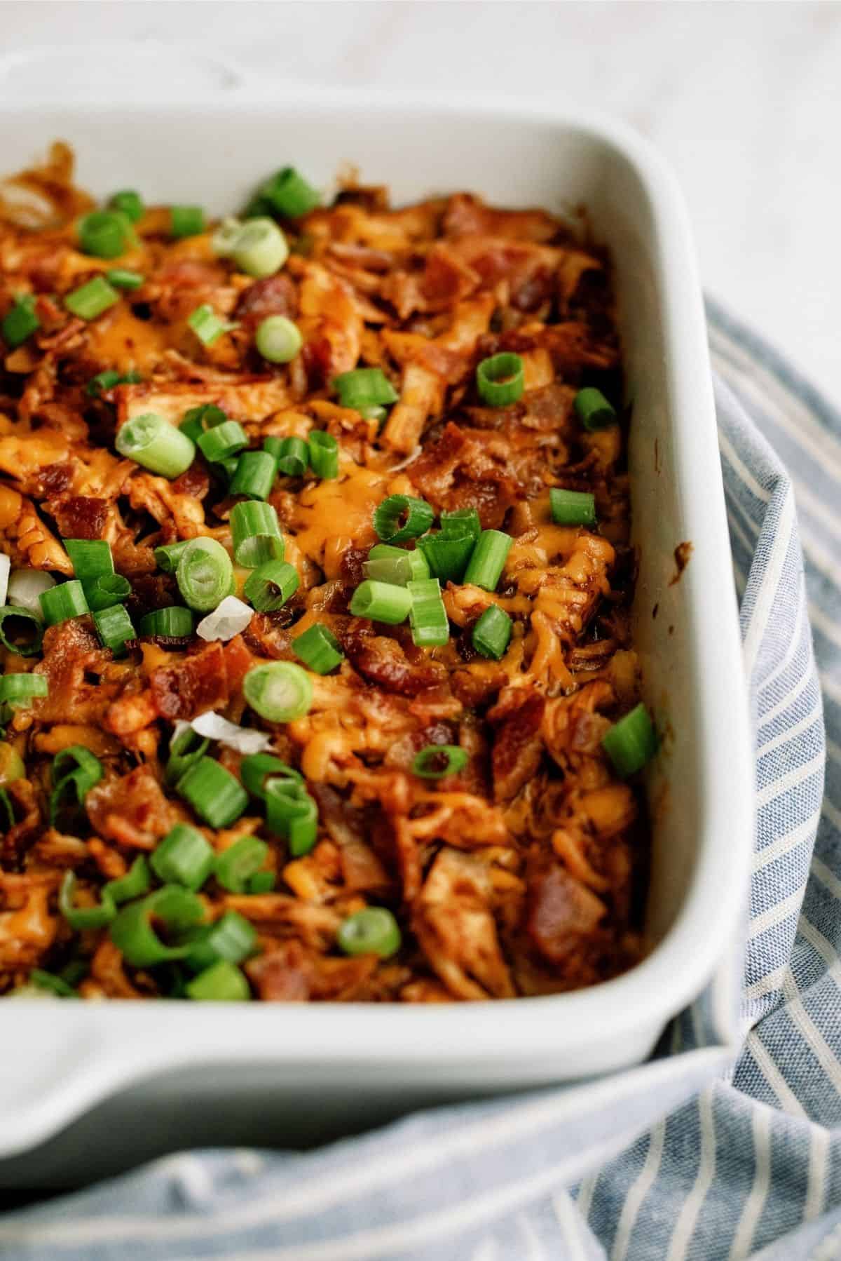 BBQ Chicken and Potato Casserole in a white casserole dish with a striped dish towel