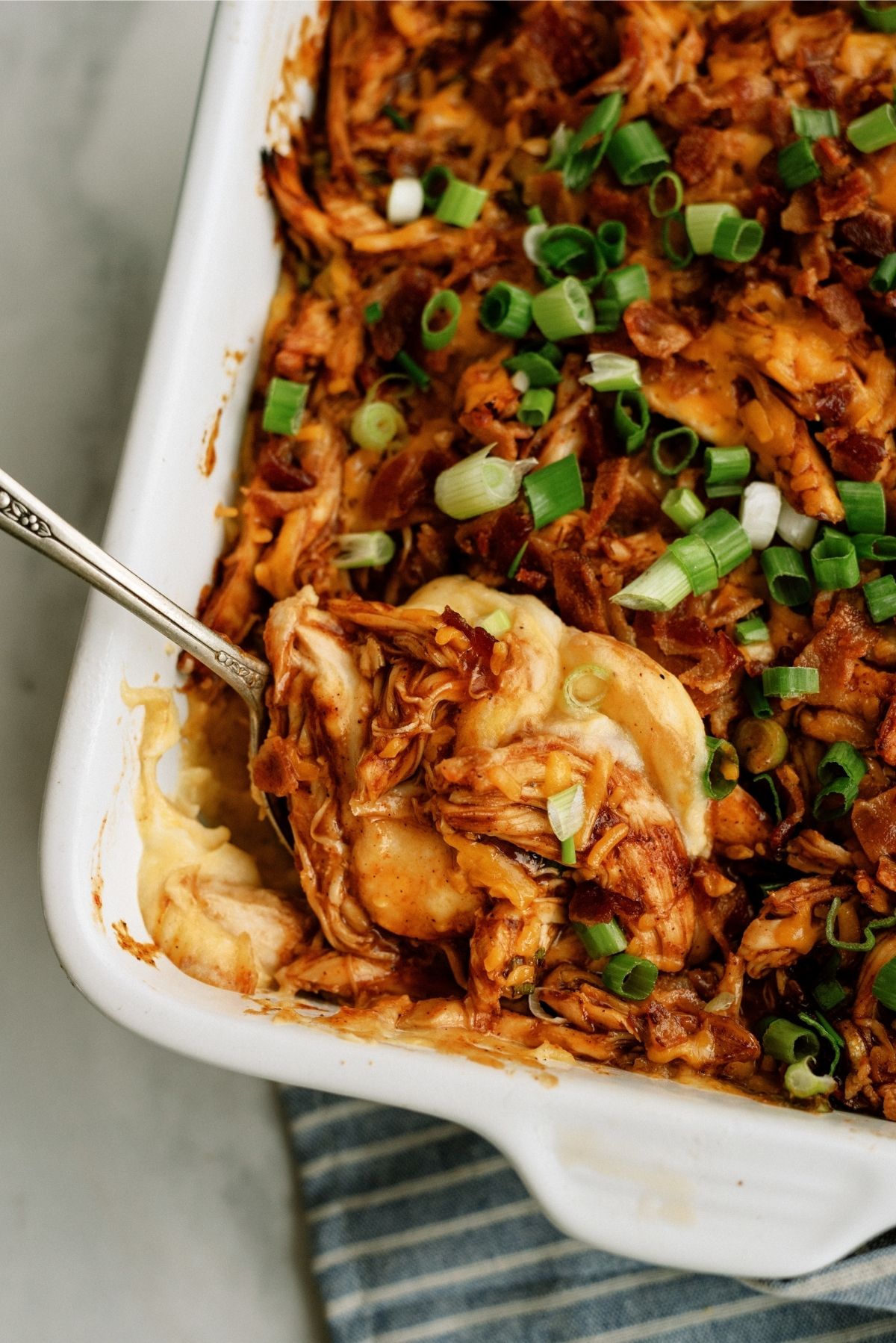 BBQ Chicken and Potato Casserole in a casserole dish with a serving spoon