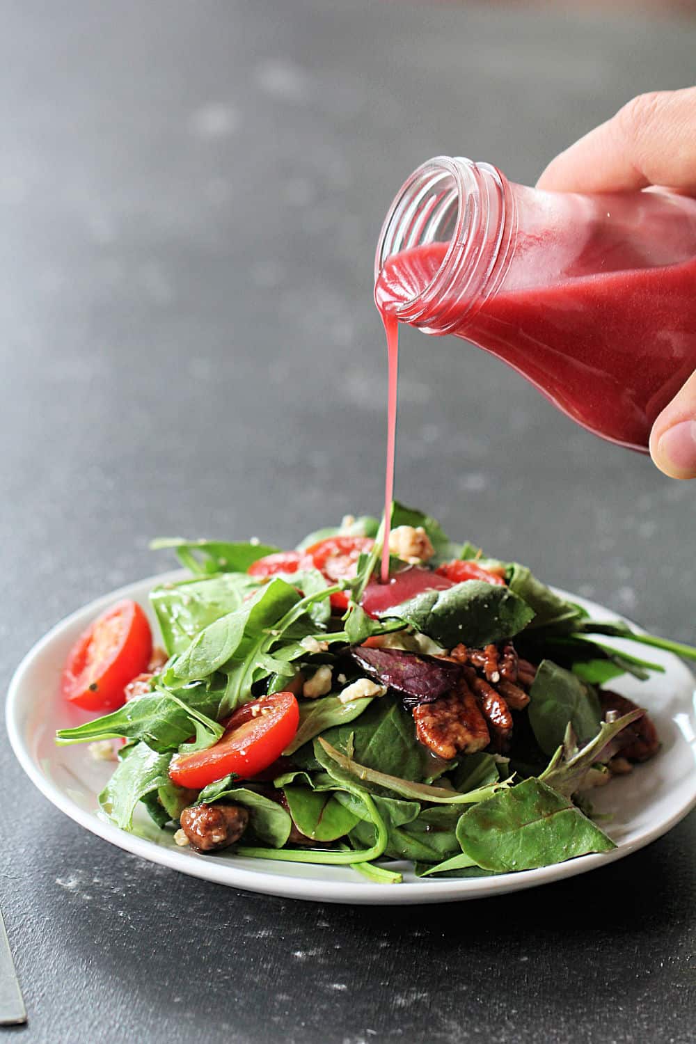 California Salad on a plate with Raspberry Vinaigrette Dressing being poured on top