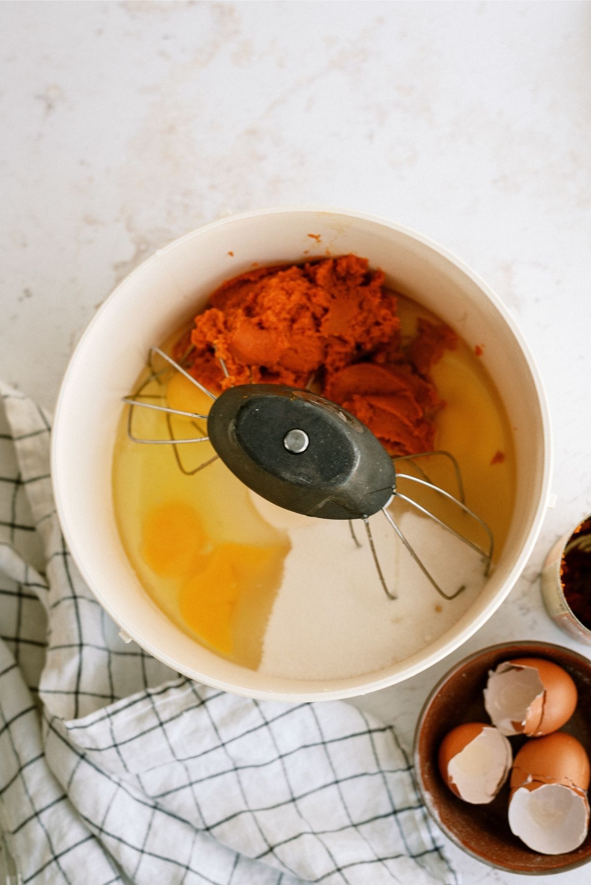 Eggs, sugar, oil and pumpkin in a stand mixing bowl