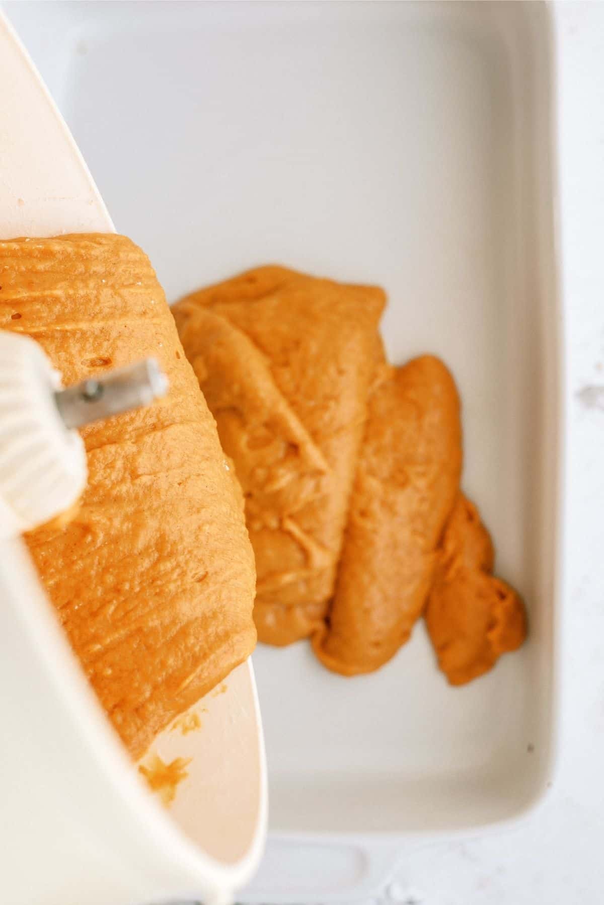 Pouring batter for Caramel Pumpkin Poke Cake into 9x13 pan