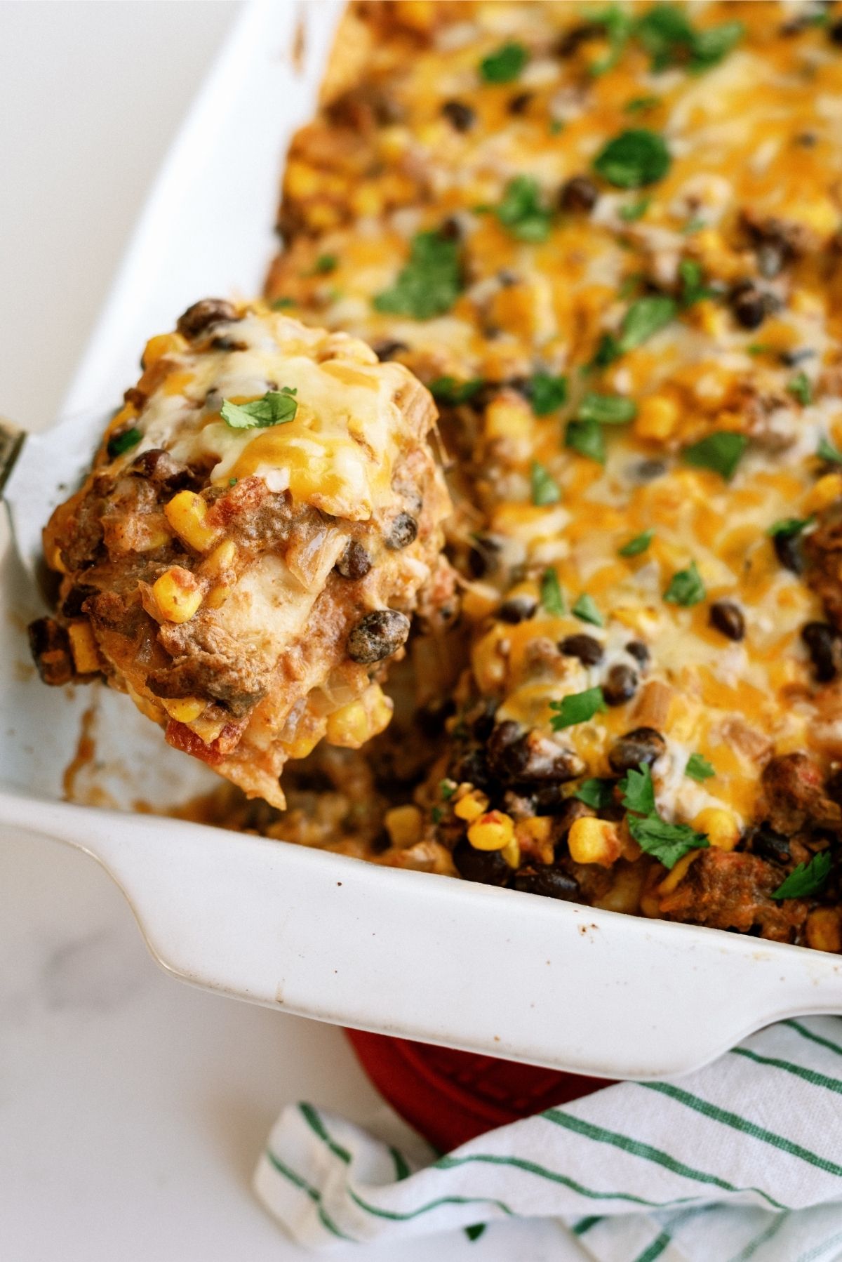 Cheesy Beef Enchilada Casserole with a slice being lifted out of the pan