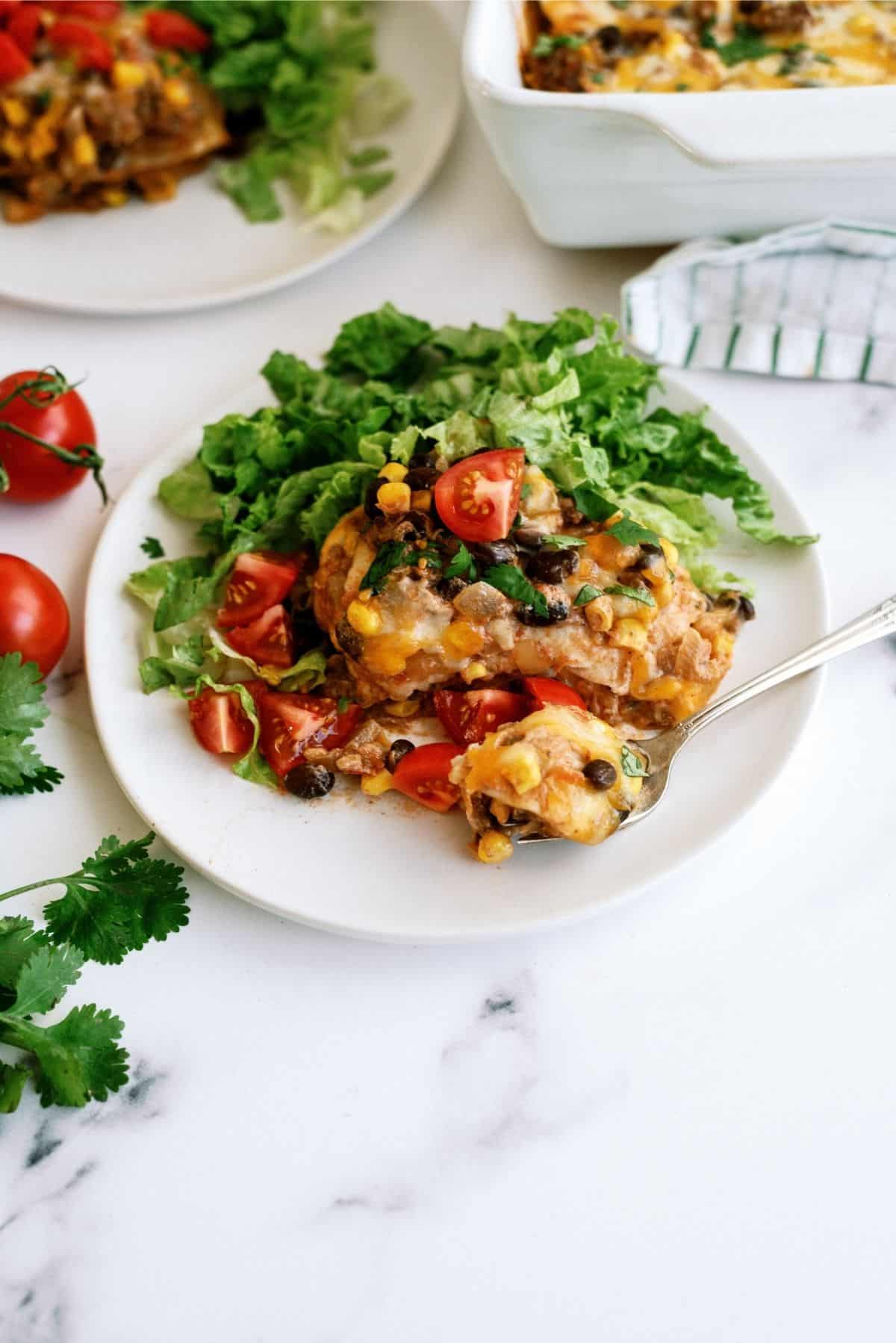 Cheesy Beef Enchilada Casserole served on a white plate with a side salad