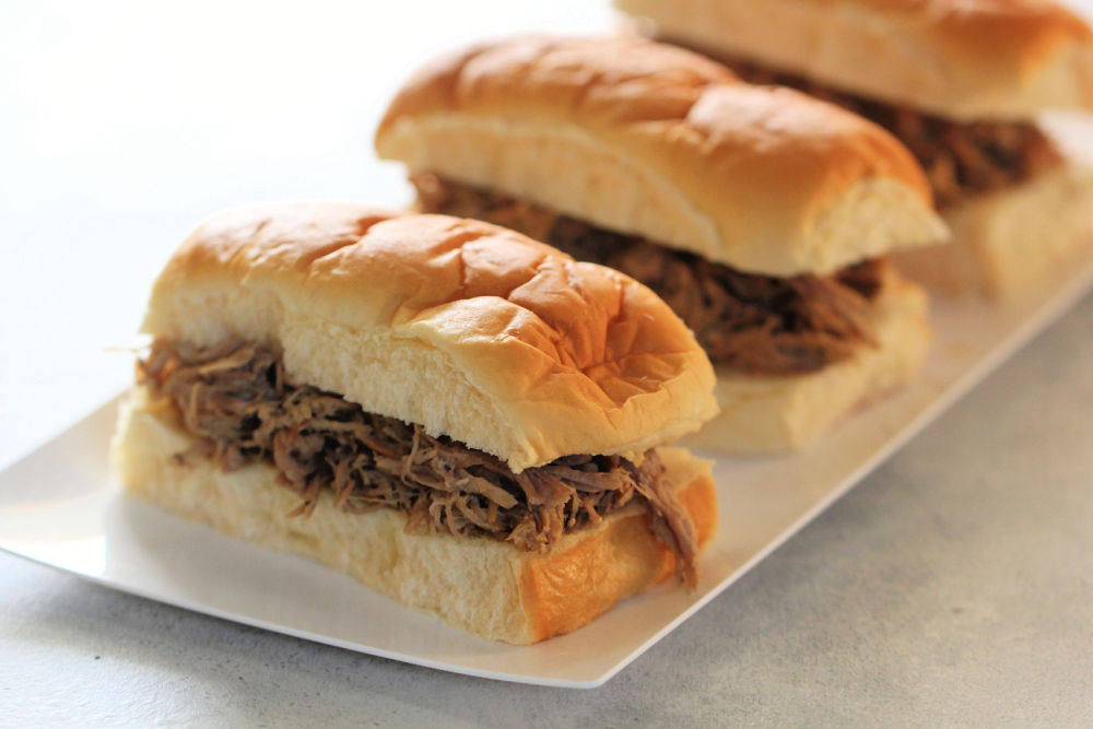 Slow Cooker Citrus Onion Pork Sliders on a white plate ready to serve