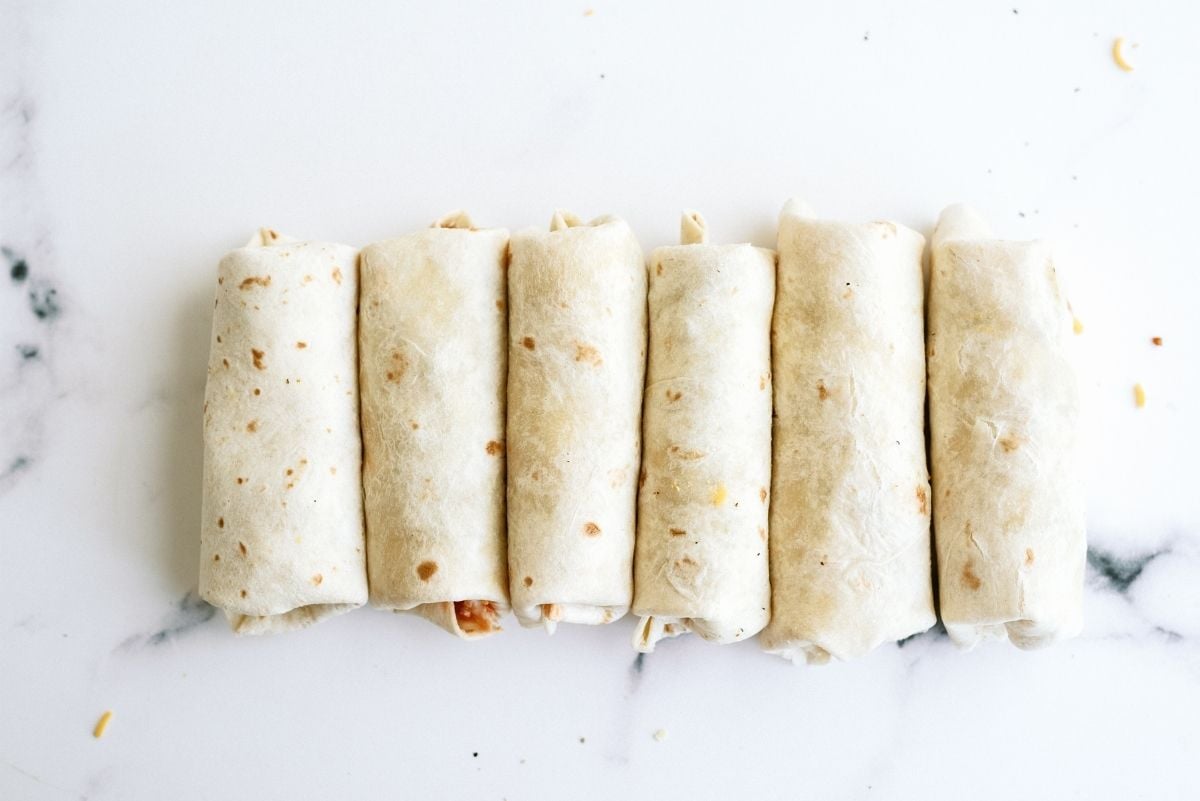 Freezer Breakfast Burritos rolled and placed seam side down in a row