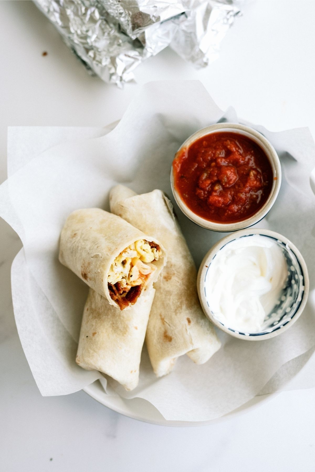 Freezer Breakfast Burritos on a plate with salsa and sour cream dipping sides