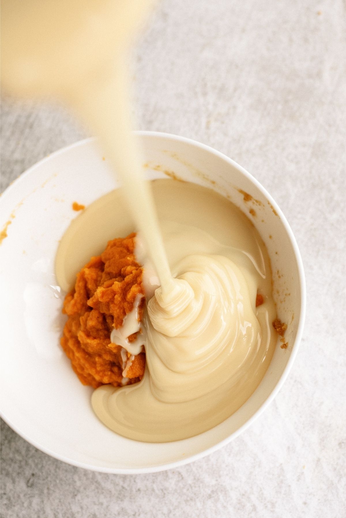 Sweetened Condensed milk combined with pumpkin puree and pumpkin spice in a white bowl