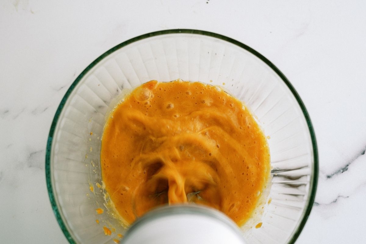 Mixing bowl with egg. oil and pumpkin puree mixed with a hand mixer