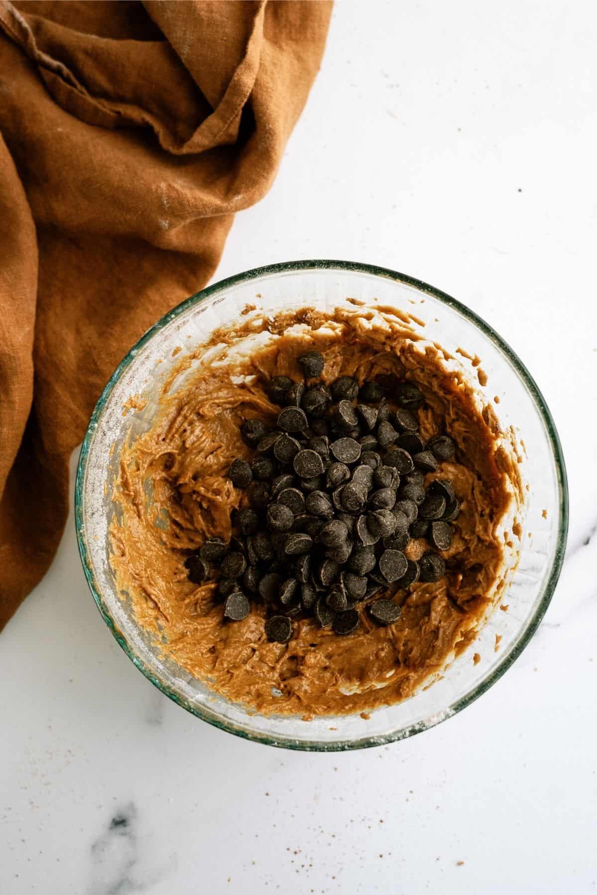 Chocolate chips with brownie batter in mixing bowl