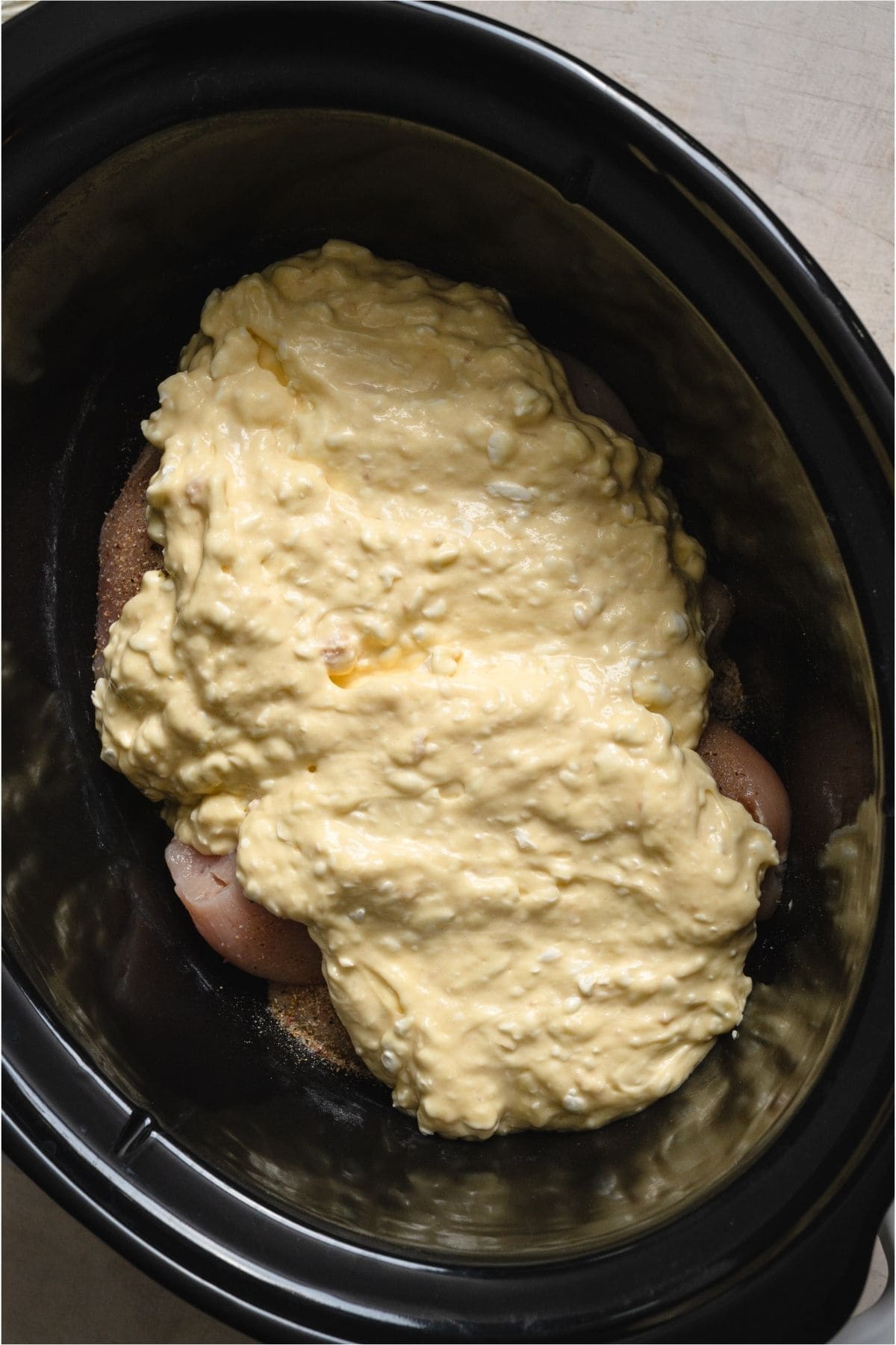 Cream sauce spread over chicken in bottom of slow cooker.