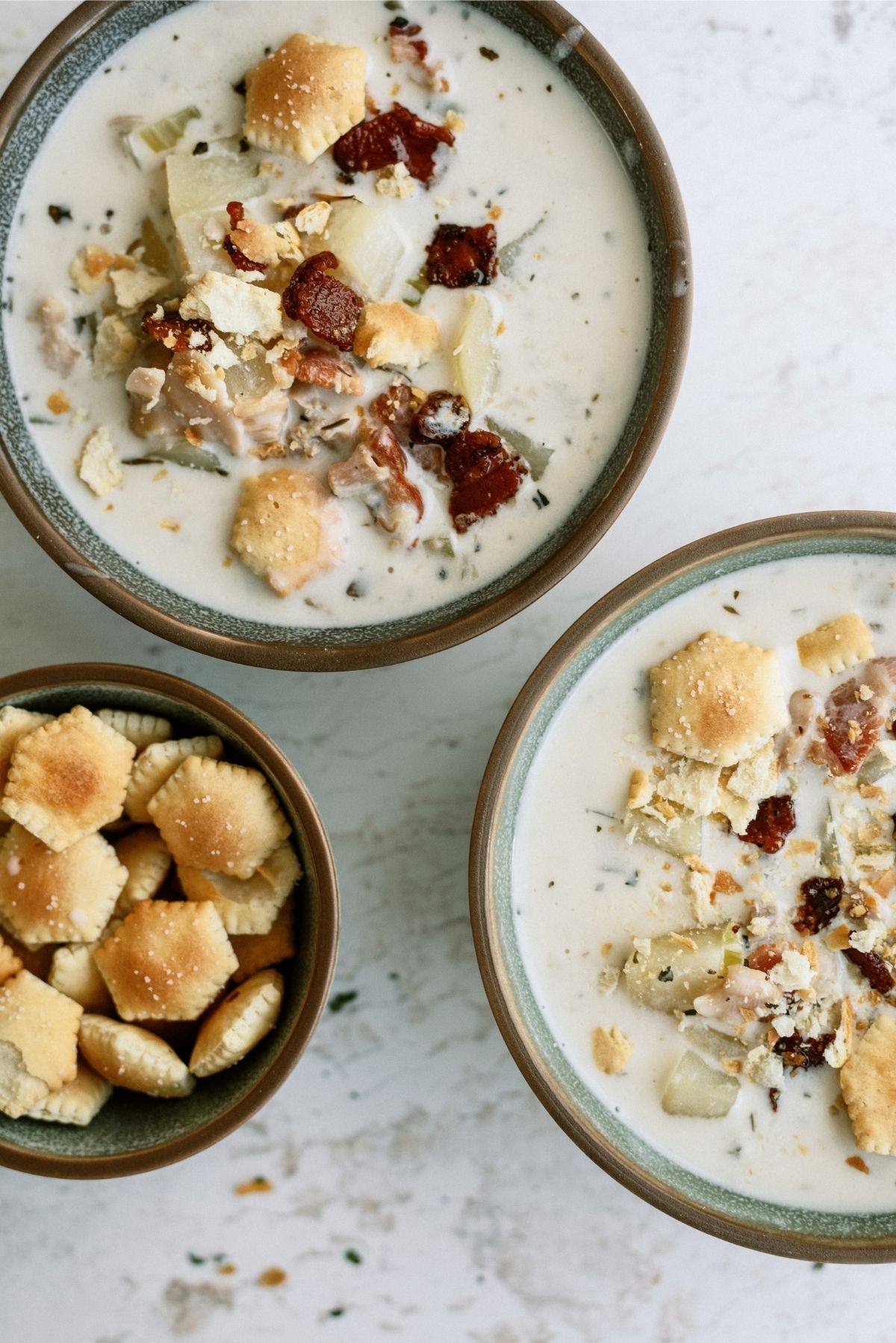 Slow Cooker New England Clam Chowder in 2 bowls with a small bowl of crackers