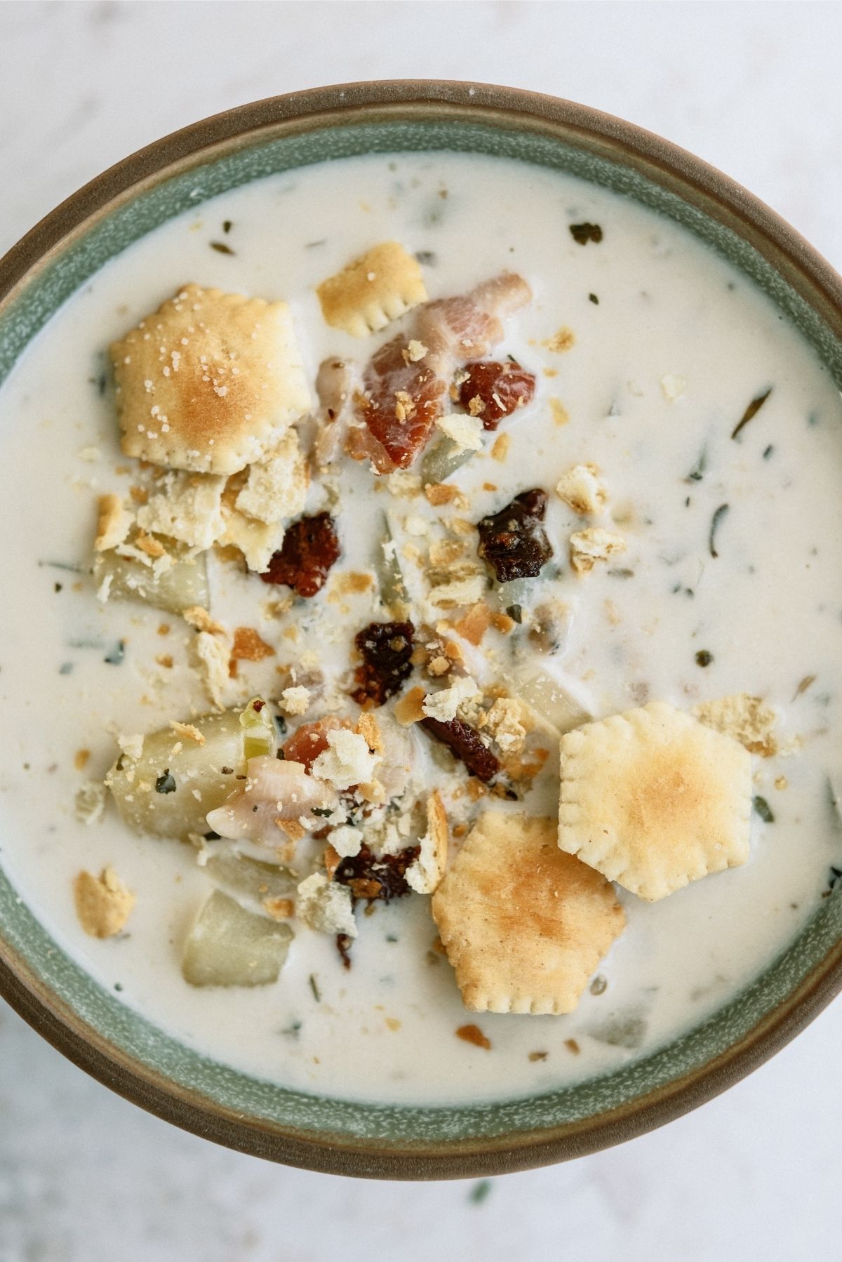 A bowl of Slow Cooker New England Clam Chowder with crackers on top