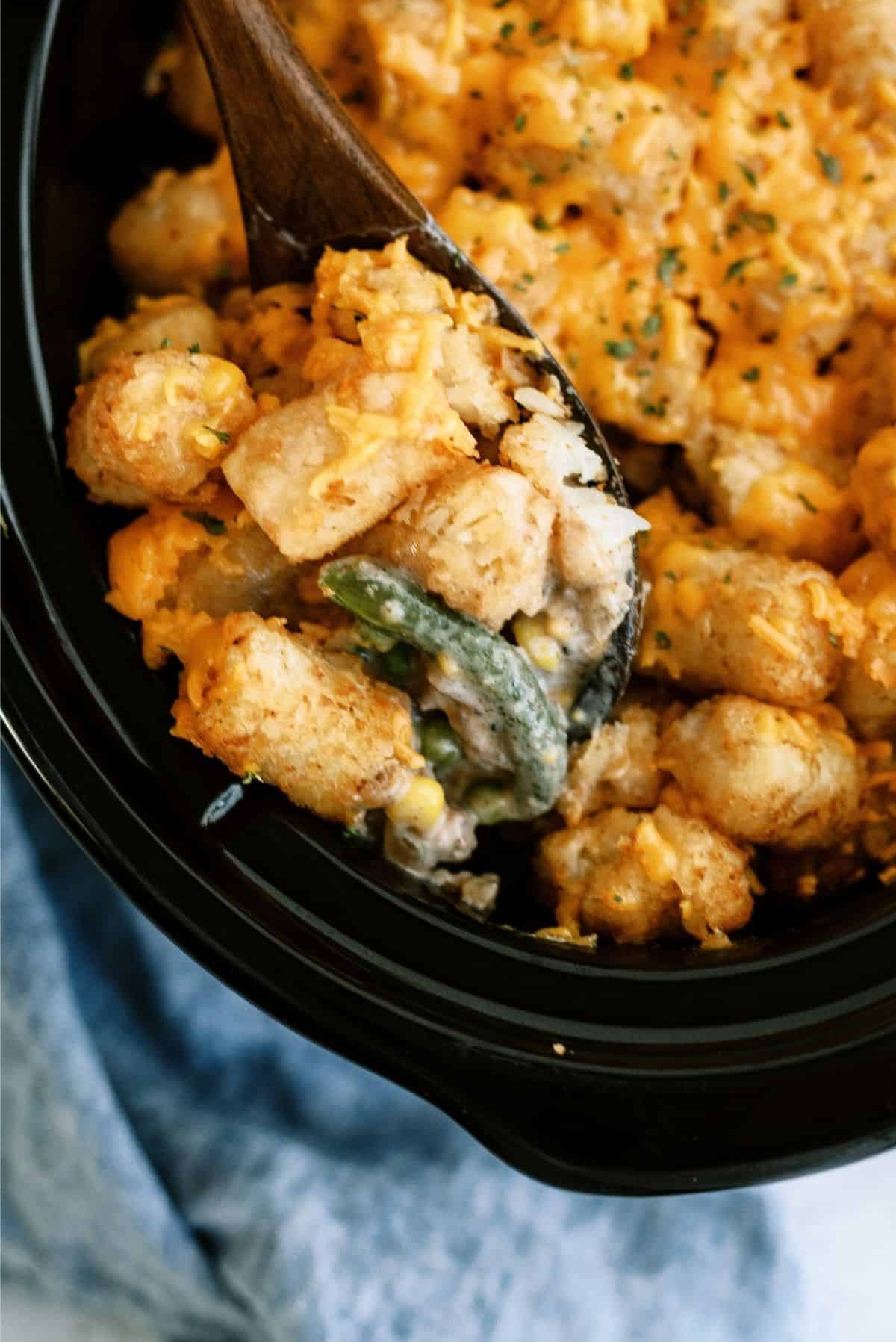 Slow Cooker Tater Tot Cowboy Casserole in the slow cooker with a serving spoon