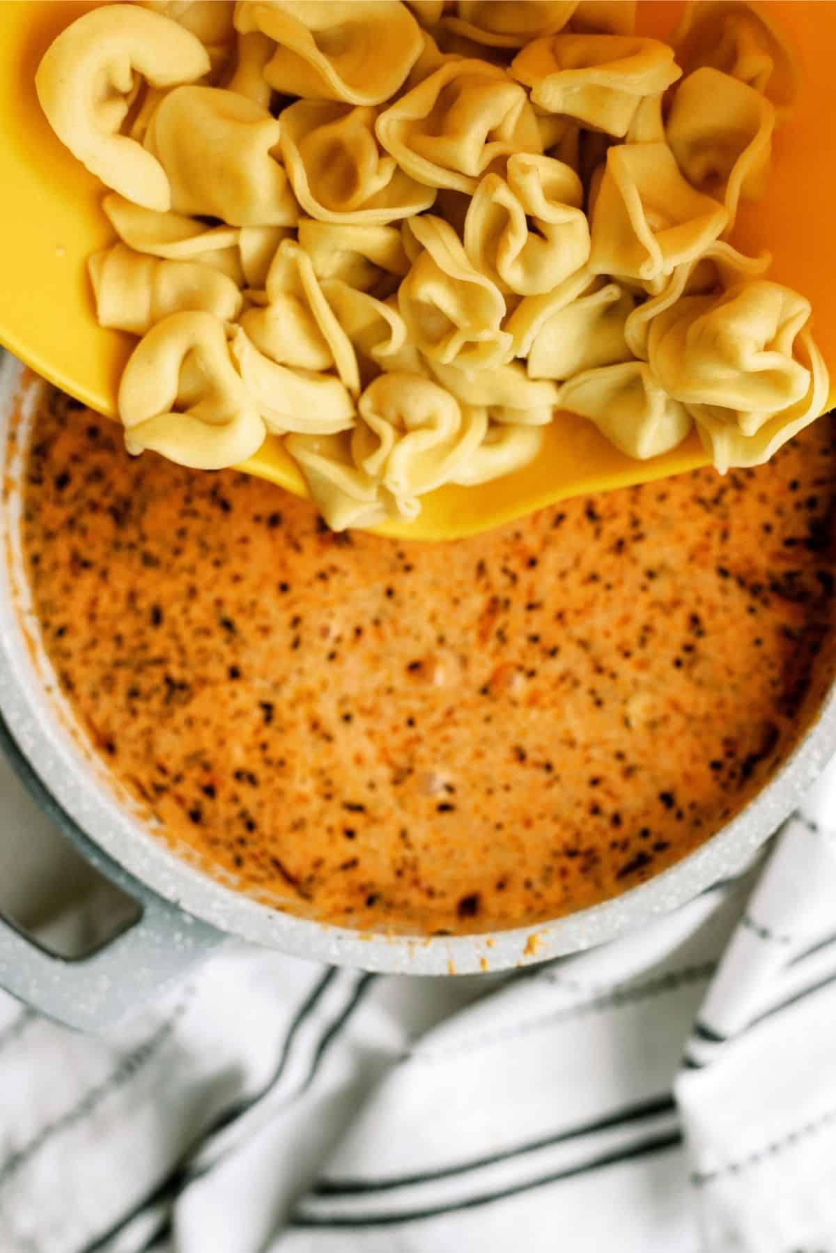 Adding cooked tortellini to soup in stock pot